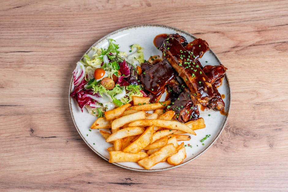 BBQ ribs being brushed with sauce on a grill.