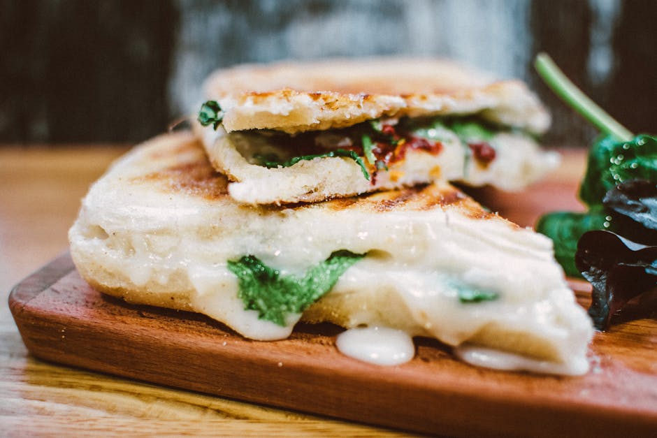 Gourmet sandwiches and paninis cut and stacked on a plate.